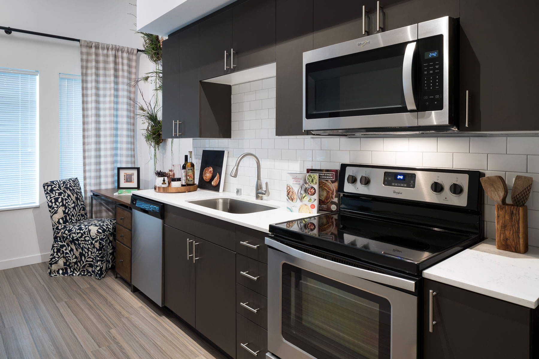 Close up of stainless steel electric kitchen stove and oven, and microwave with white subway tile backsplash